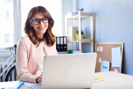 a woman smiling while using a laptop